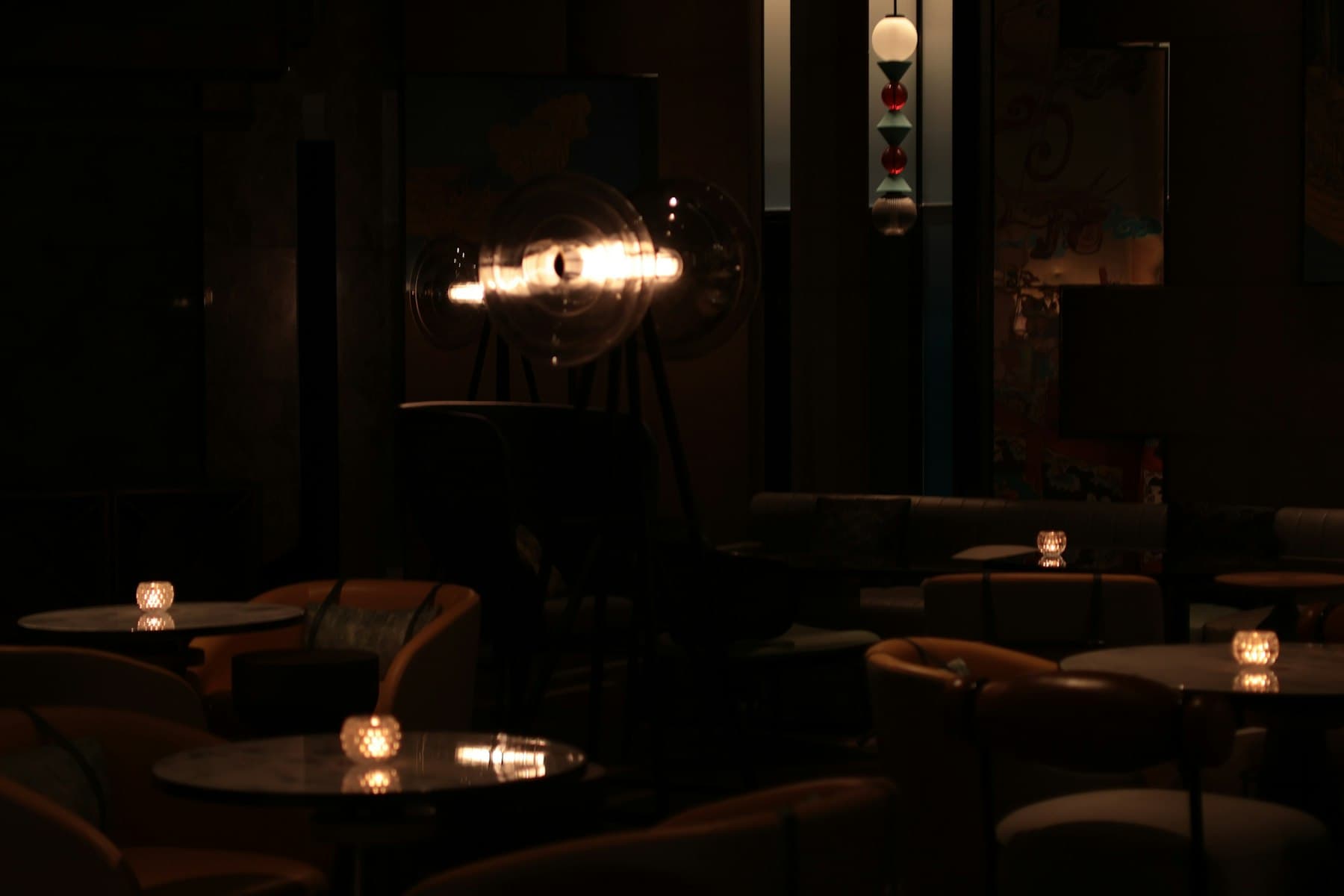 A dark lounge at night, lit by small candles on marble tables