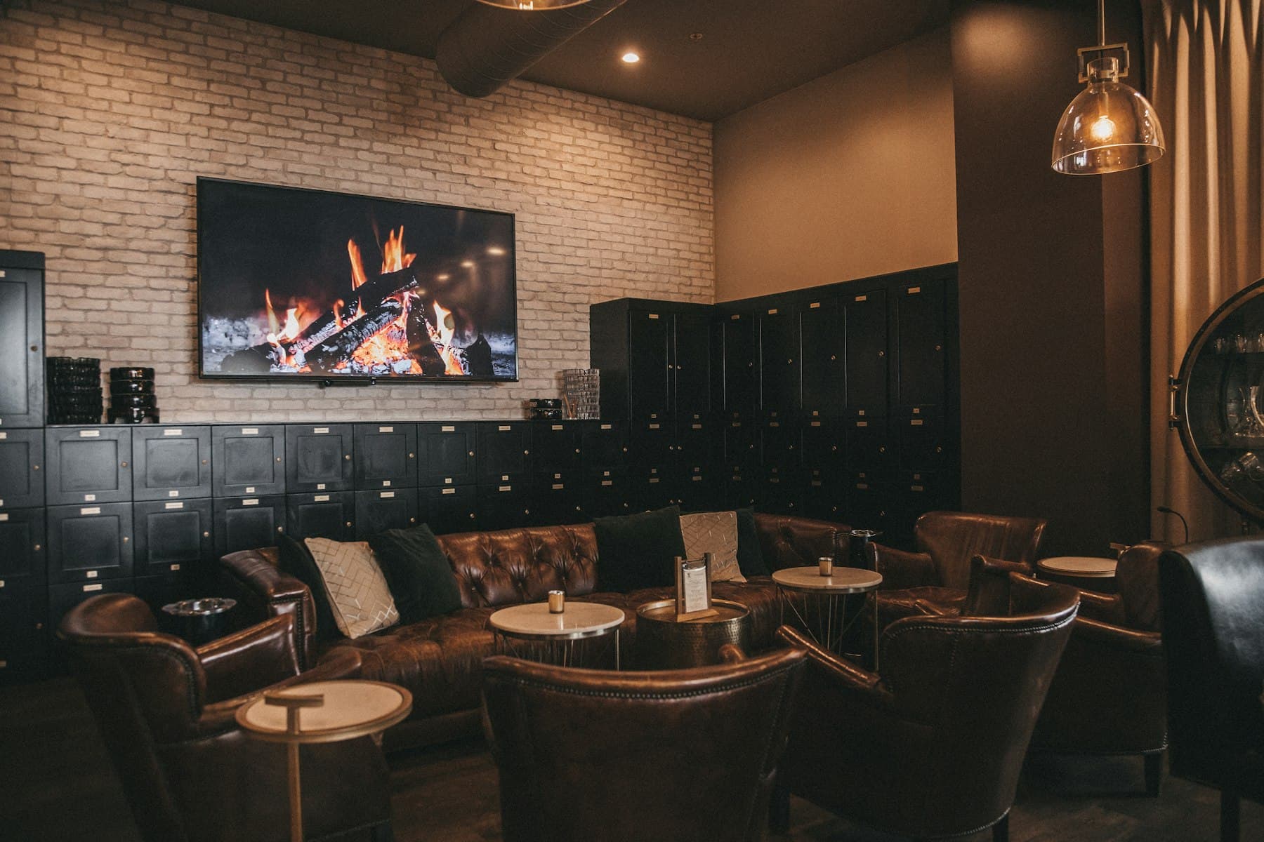 A cigar lounge with leather chesterfield sofas in front of a wall of member lockers